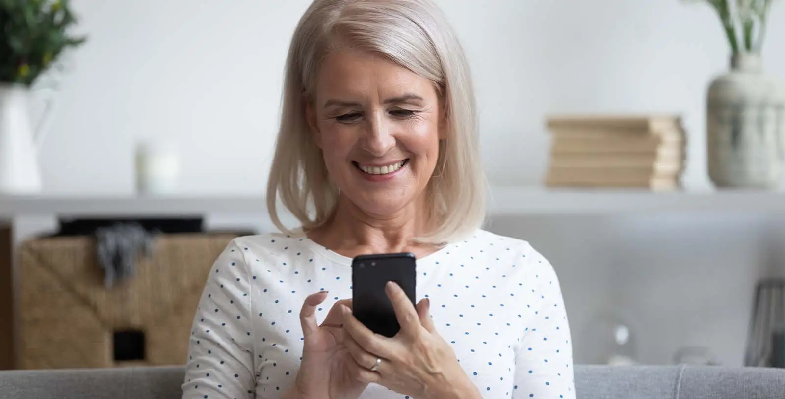 a happy middle-aged woman using Propline property management app in her smartphone and happy with her easy investment